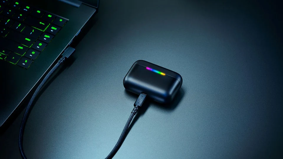 Czarny dysk zewnętrzny podłączony do laptopa za pomocą kabla USB, z kolorowym podświetleniem LED pośrodku obudowy dysku.
