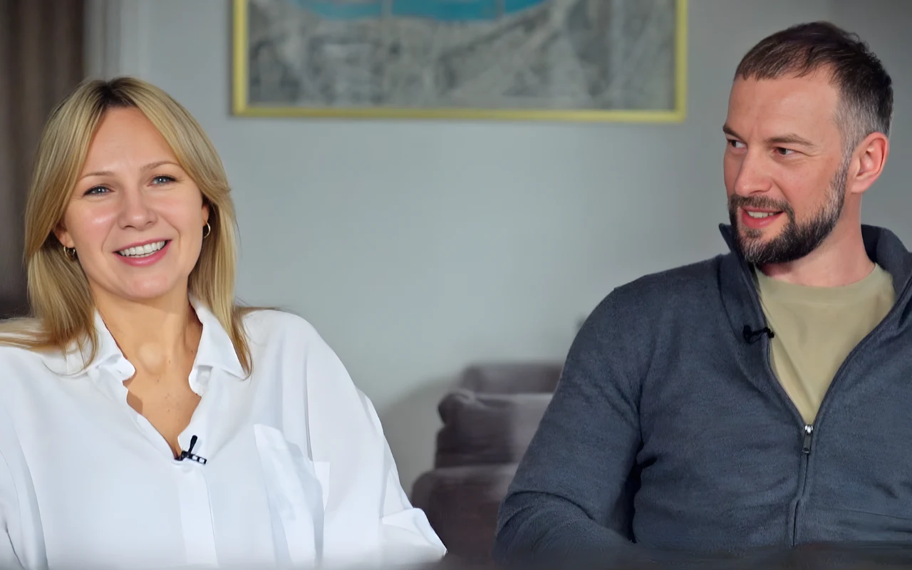 Anna Guzik i Wojciech Tylka w wywiadzie dla "halo tu polsat" Dwie osoby siedzą na kanapie, kobieta w białej koszuli uśmiecha się wprost do aparatu, mężczyzna w szarej bluzie patrzy na nią z uśmiechem.