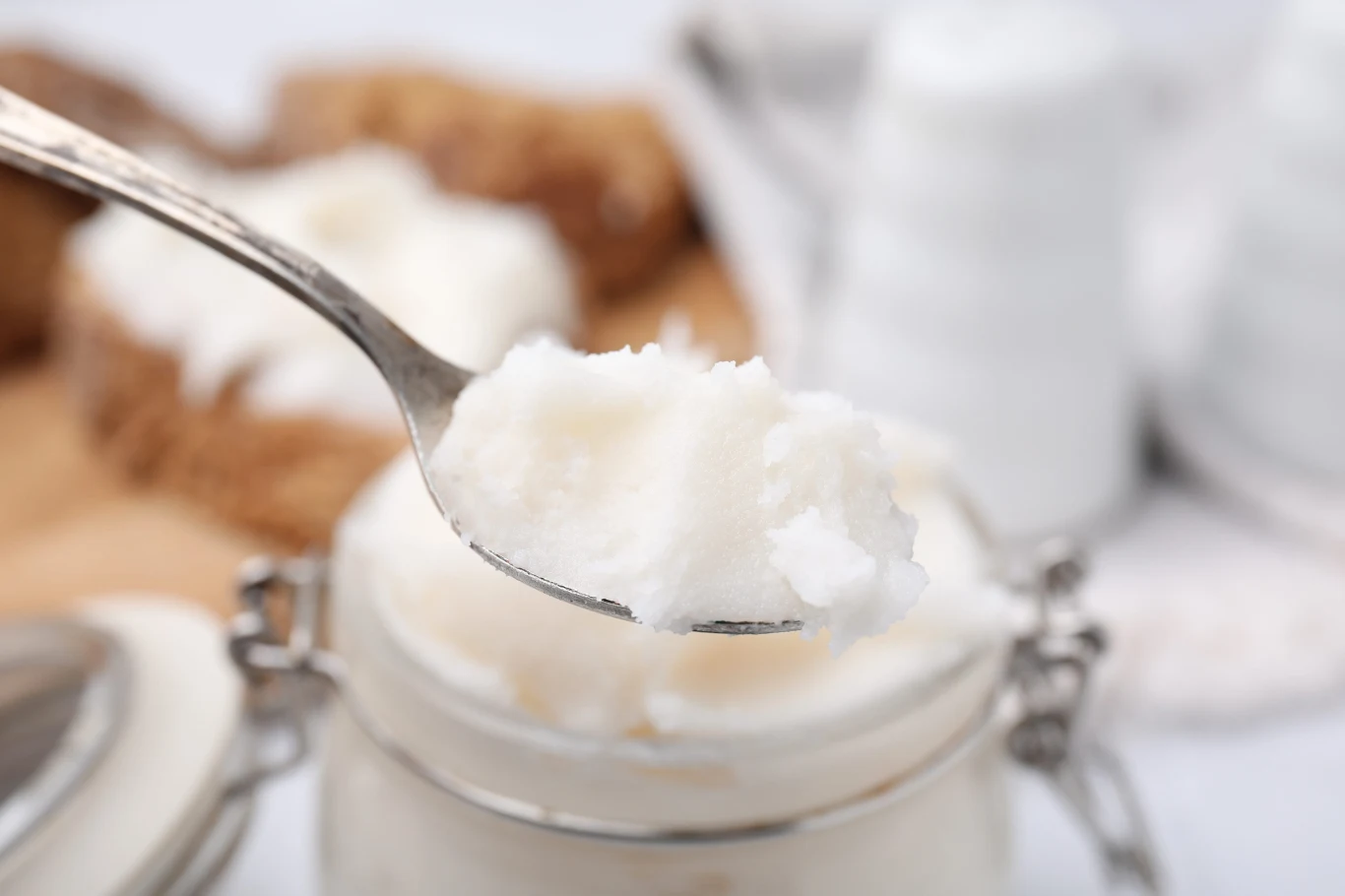 Masło kokosowe można samodzielnie przygotować w domu Łyżka z domowym masłem kokosowym nad otwartym słoikiem z tym samym produktem