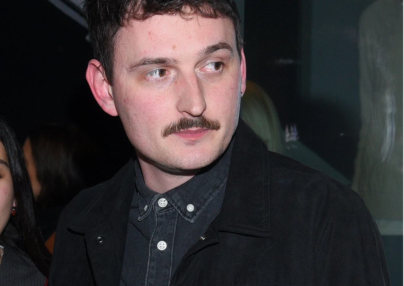 Dawid Podsiadło Dawid Podsiadło w czarnej kurtce i koszuli, z krótkimi ciemnymi włosami i wąsem; spogląda w bok