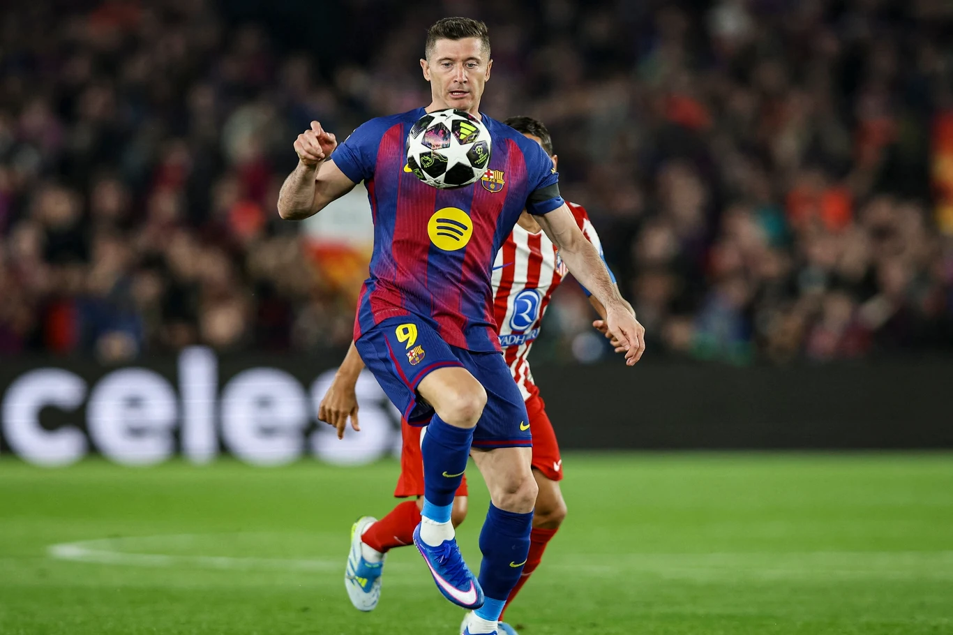 piłkarz w stroju FC Barcelony z numerem 9 kontroluje piłkę podczas meczu, skoncentrowany na akcji, w tle zawodnik drużyny przeciwnej oraz zapełnione trybuny stadionu