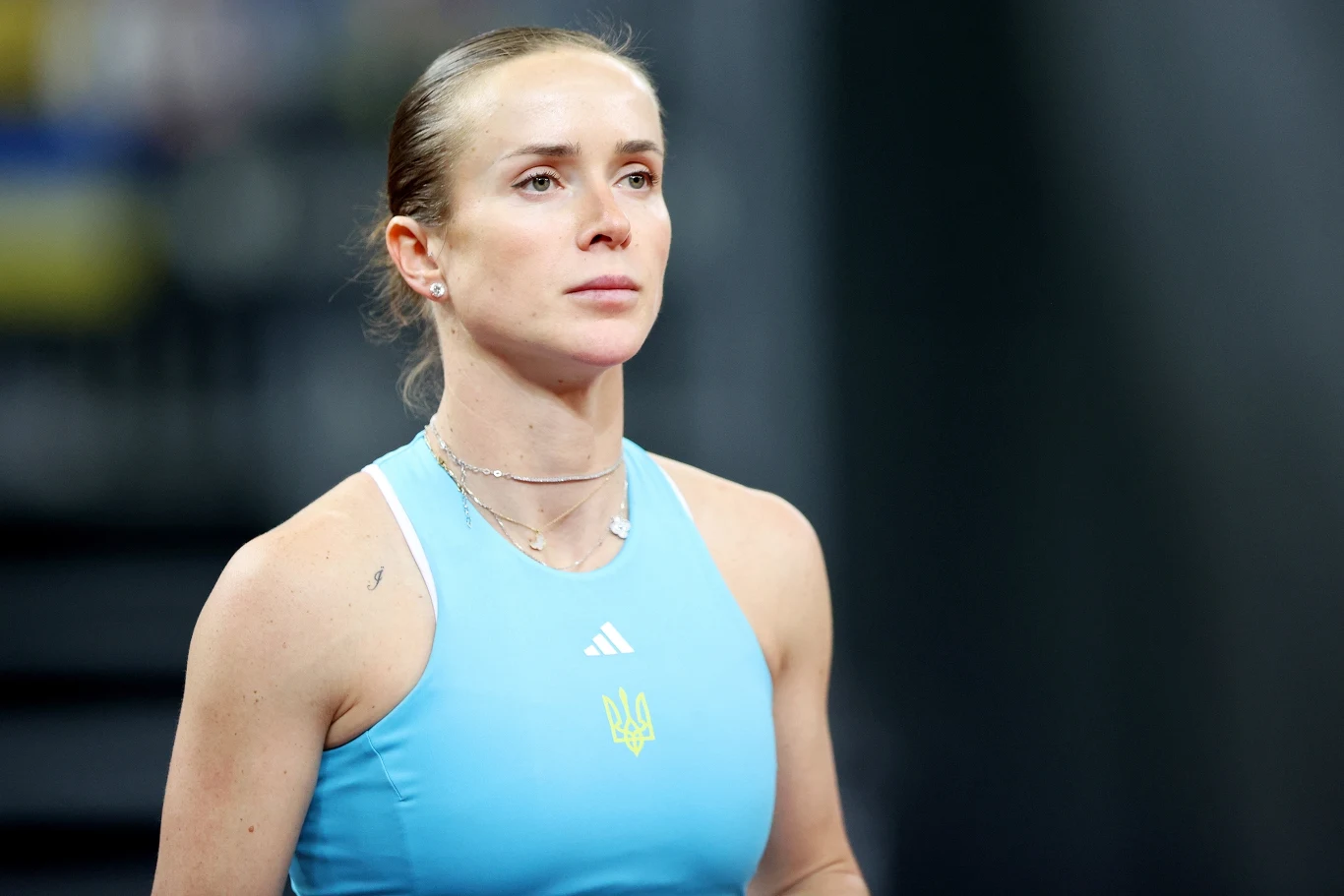 Elina Switolina kobieta w sportowym topie koloru błękitnego z godłem Ukrainy i logotypem Adidas, ma spięte włosy i skupiony wyraz twarzy