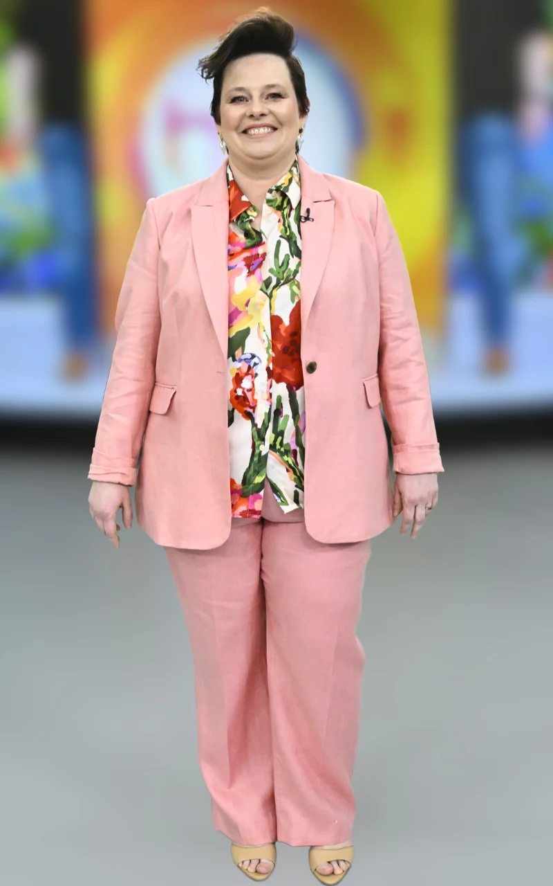 Spektakularna metamorfoza widzki "halo tu polsat". Małgorzata wyglądała jak gwiazda uśmiechnięta kobieta w różowym garniturze z kolorową koszulą w kwiaty, stojąca frontalnie na neutralnym tle, z krótkimi, ciemnymi włosami i jasnymi sandałami