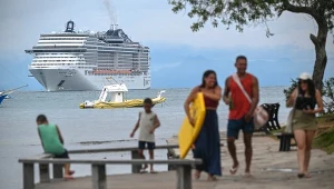 Turyści spacerują po promenadzie Orla Brigitte Bardot w mieście Armacao Dos Búzios w stanie Rio de Janeiro w Brazylii, w tle statek wycieczkowy