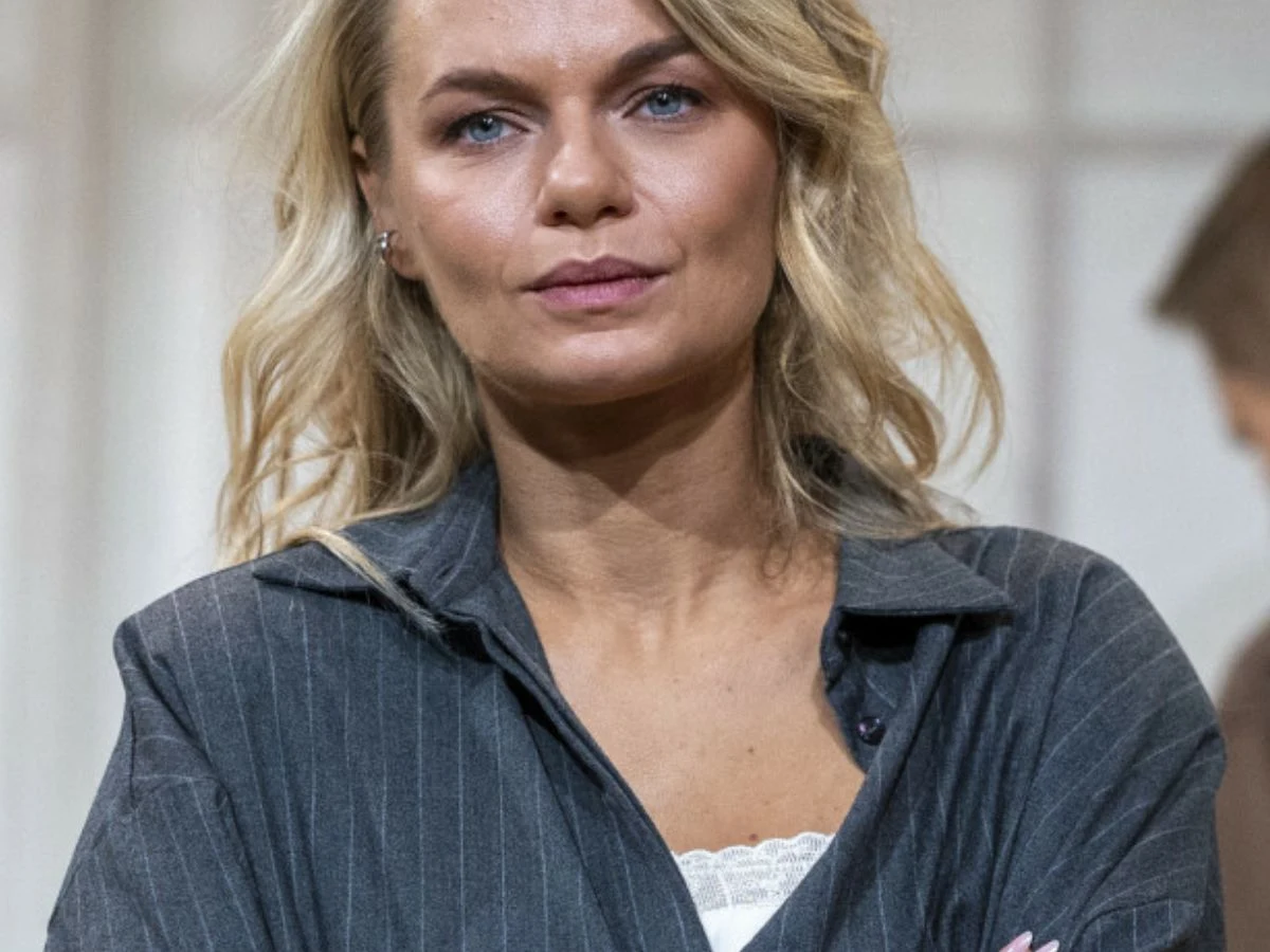 Emilia Komarnicka Emilia Komarnicka w szarej, pasiastiej marynarce, z blond włosami i niebieskimi oczami, patrzy przed siebie.