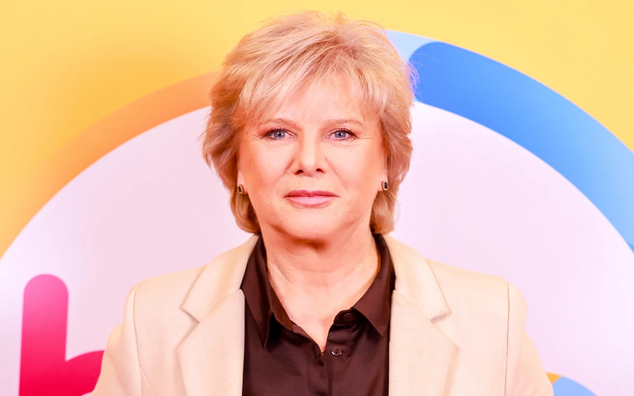 Dorota Kamińska w "halo tu polsat" Dorota Kamińska w "halo tu polsat". Aktorka w jasnej marynarce i ciemnej koszuli na tle logo programu