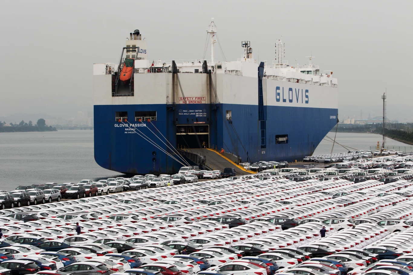 Hyundai zmienia trasy dostaw. Wojna utrudnia logistykę i produkcję aut. Statek transportowy Glovis przy nabrzeżu, rampa załadunkowa i setki nowych aut czekające na eksport