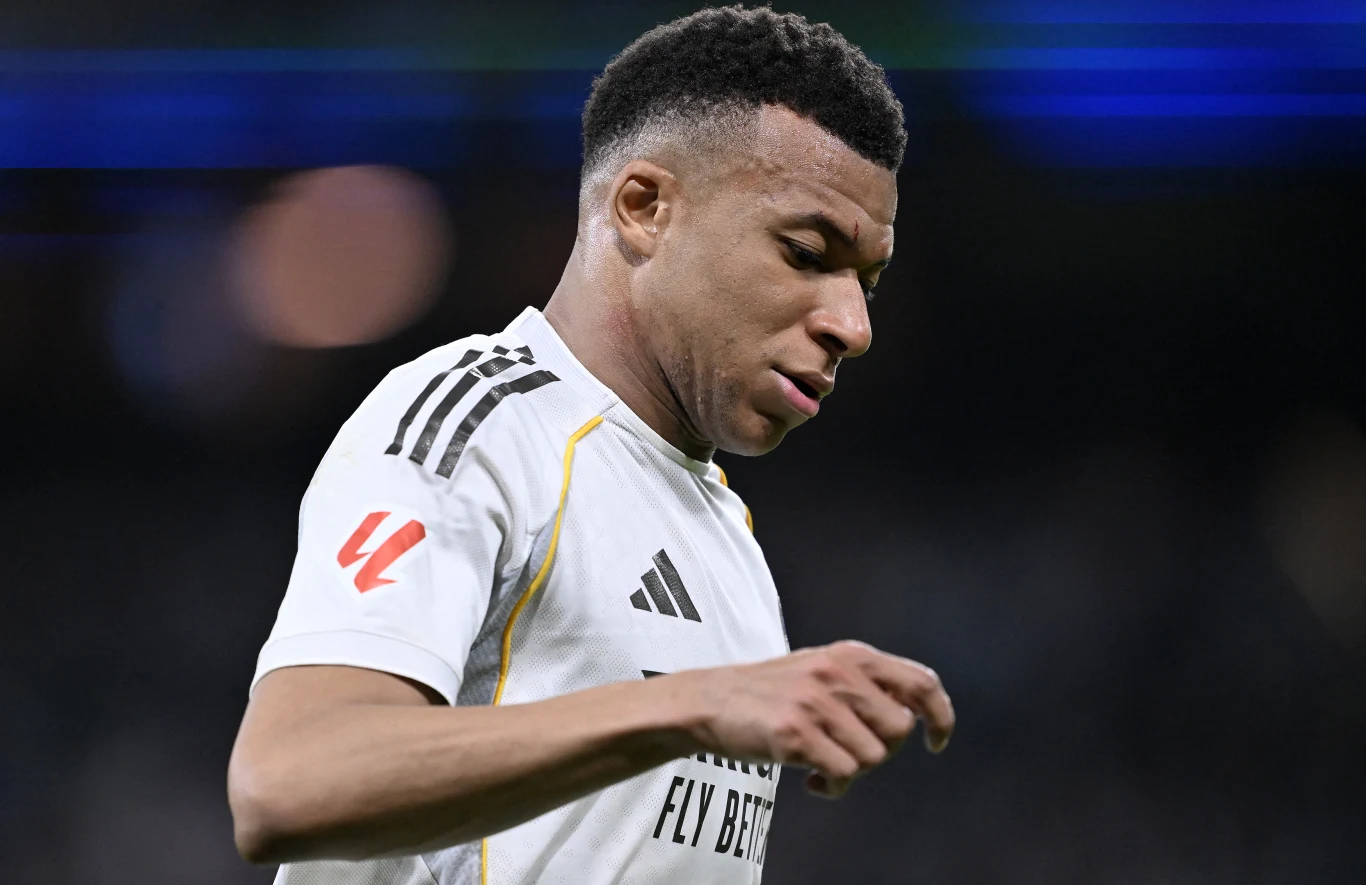 Kylian Mbappe Kylian Mbappe w białej koszulce z czarnymi i żółtymi akcentami podczas meczu na stadionie przy świetle lamp
