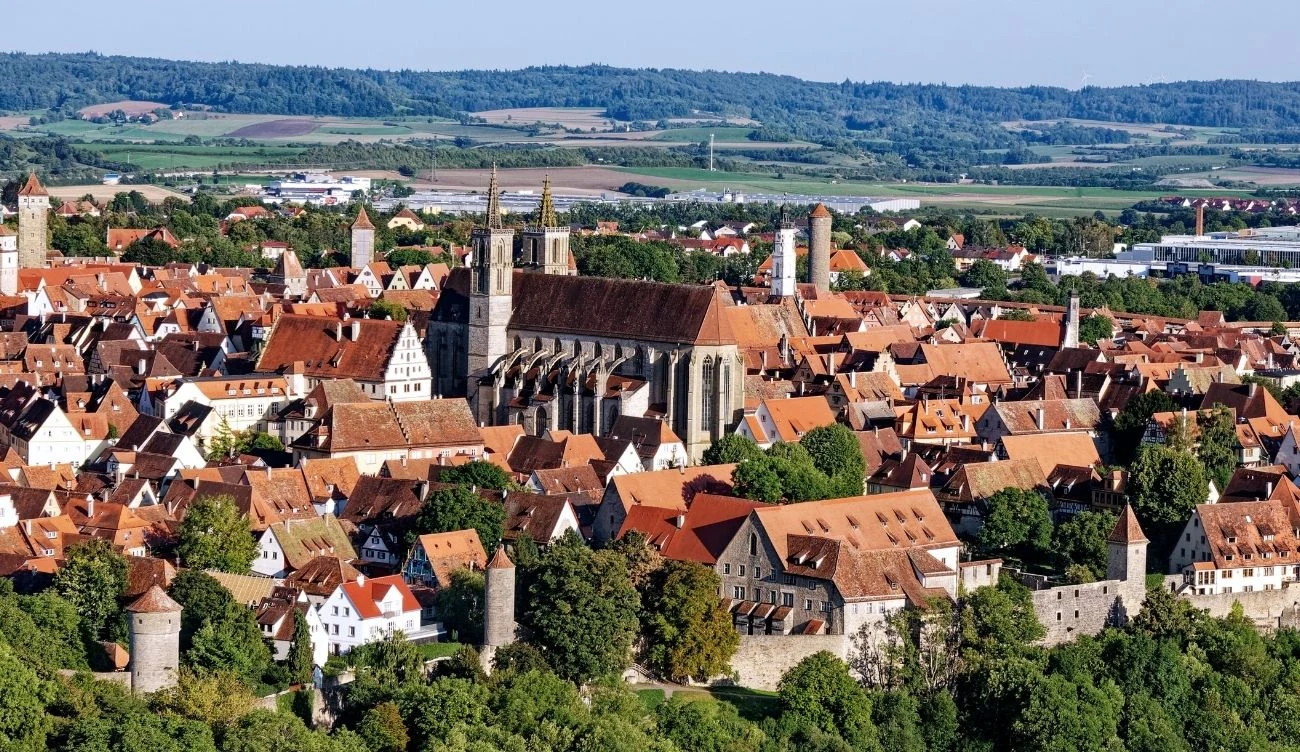 średniowieczne miasto otoczone murami obronnymi, zdominowane przez kościół o wysokich wieżach, liczne czerwone dachy, wieże strażnicze oraz malowniczo położone u podnóża zalesionych wzgórz