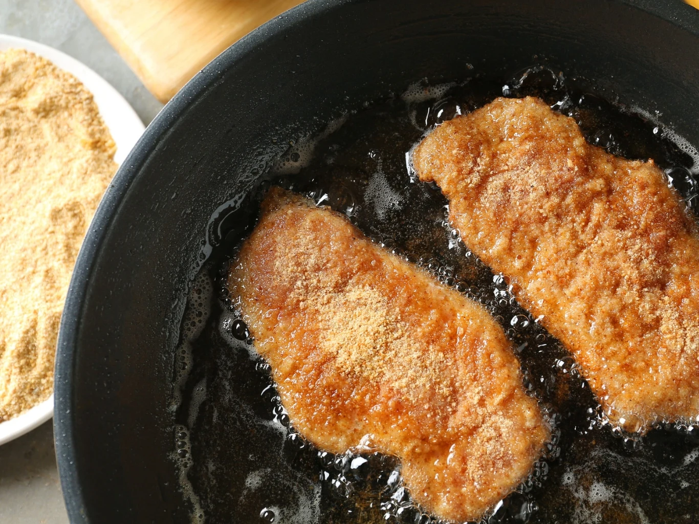 Łatwa w przygotowaniu i niedroga. Ta ryba ma też mniej znaną stronę, ponieważ może zawierać toksyny Dwa panierowane kotlety rybne smażone w głębokim tłuszczu, obok talerz z bułką tartą.