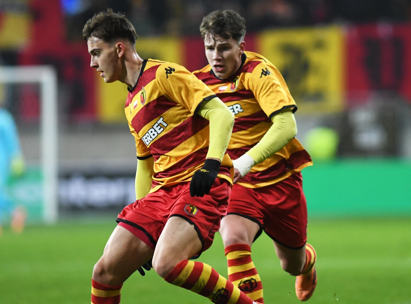 Bartosz Mazurek i Oskar Pietuszewski w barwach Jagiellonii Białystok Bartosz Mazurek i Oskar Pietuszewski w żółto-czerwonych strojach Jagiellonii podczas akcji na boisku