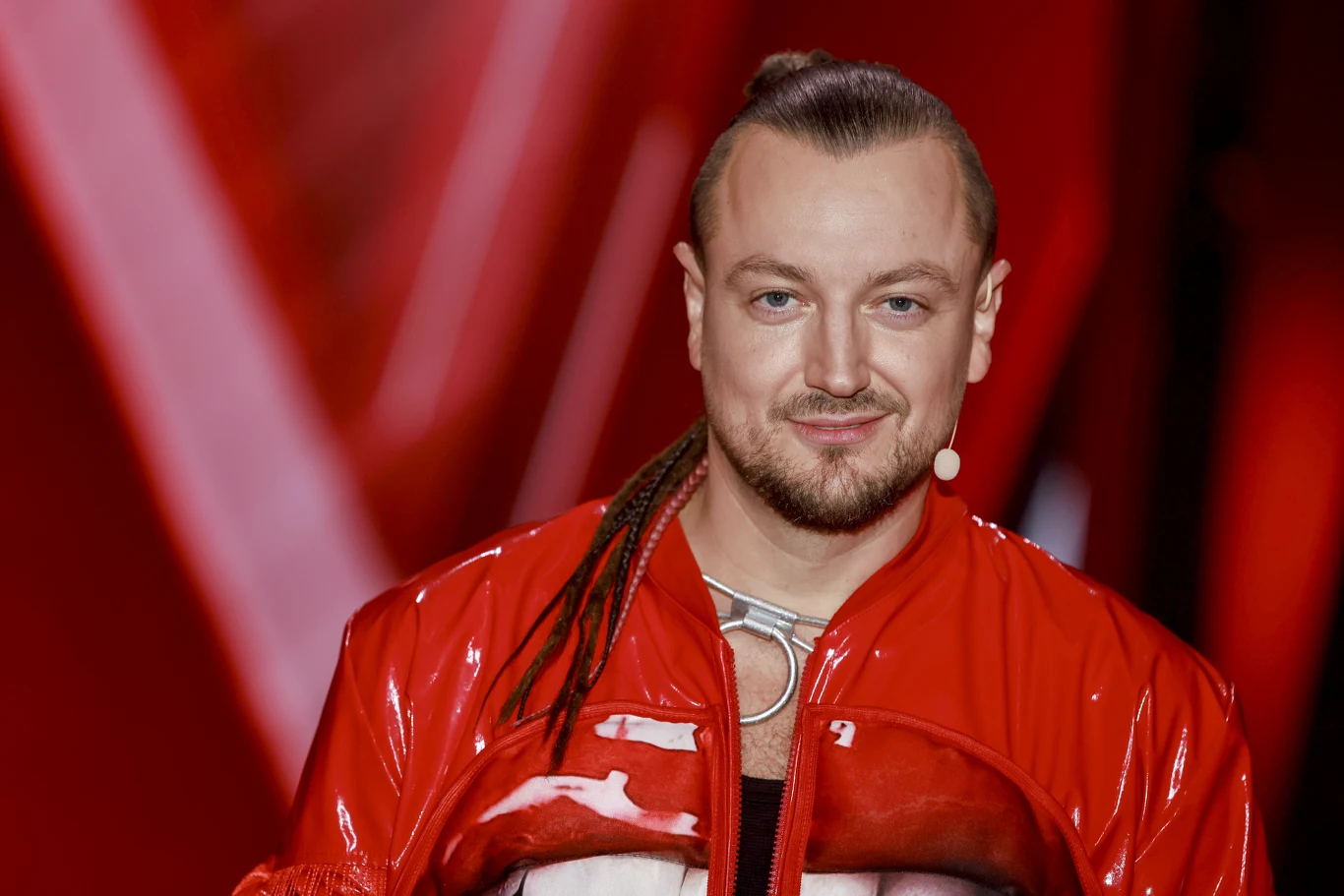 Baron jest gitarzystą grupy Afromental Baron z Afromental w czerwonej kurtce i mikrofonem nagłownym, na tle czerwonego oświetlenia sceny