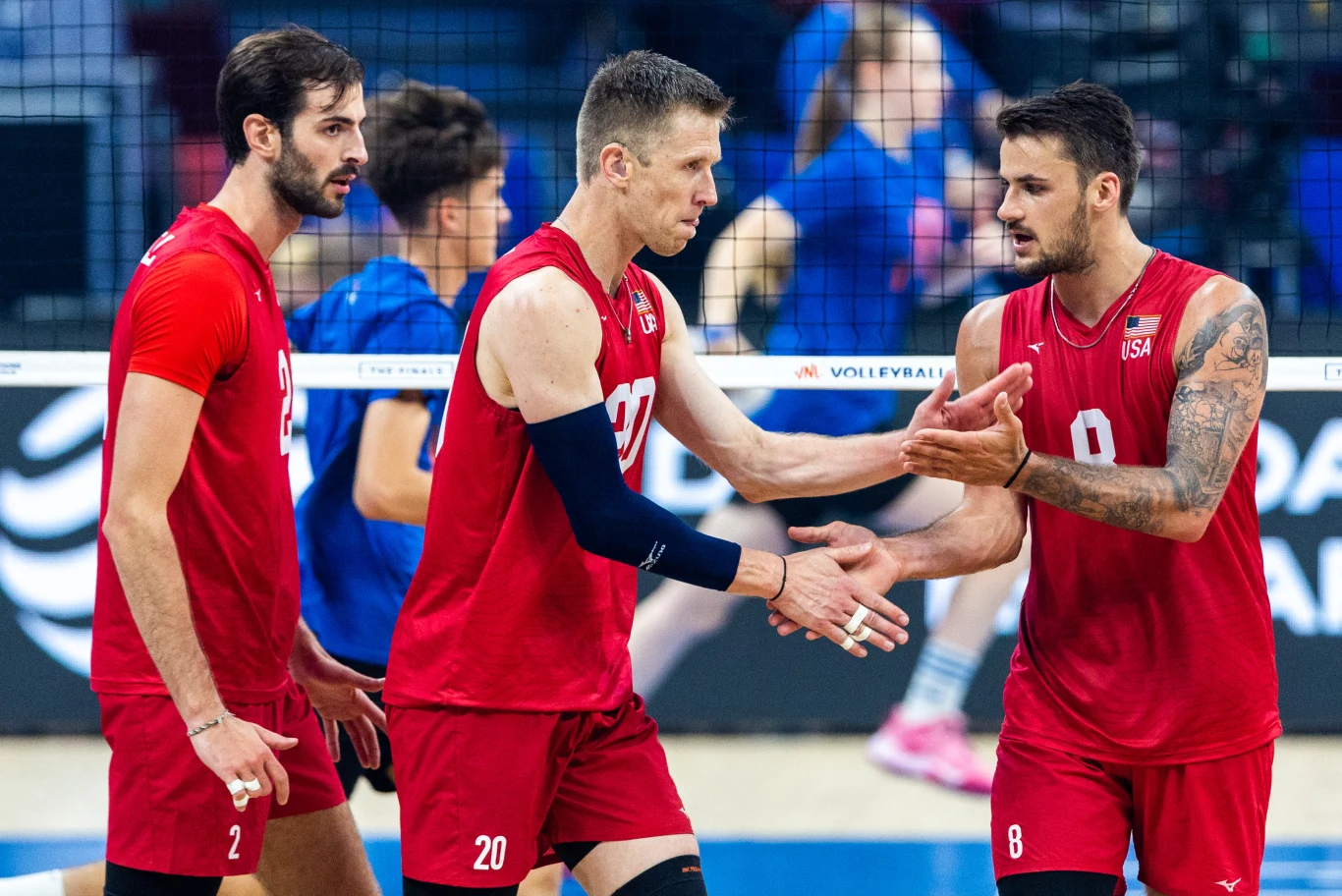 David Smith (w środku) w reprezentacji Stanów Zjednoczonych David Smith w środku, w czerwonym stroju USA, wymienia uścisk dłoni z kolegami podczas meczu siatkówki.