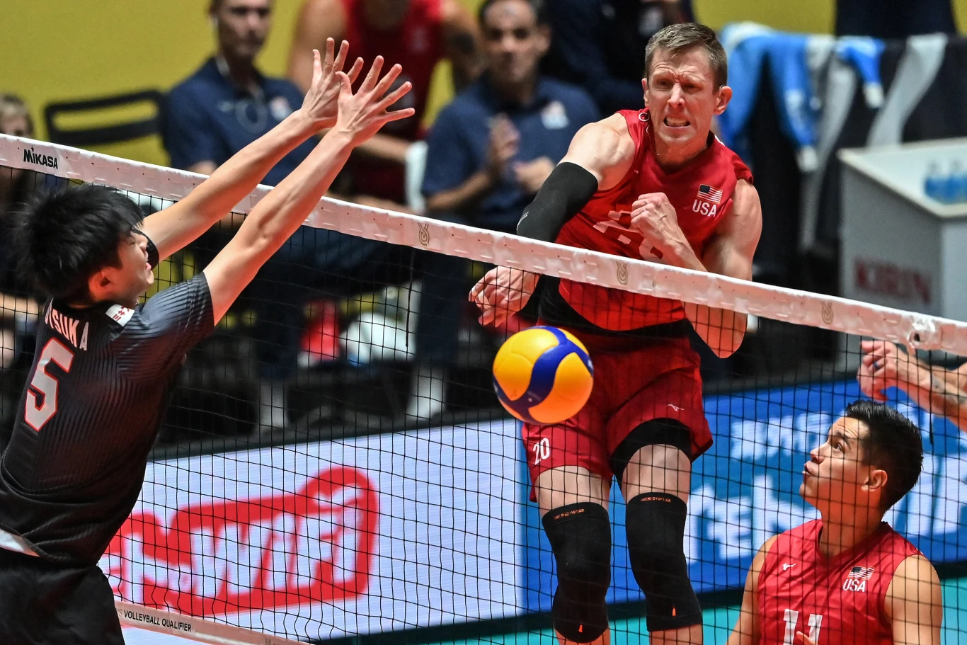 David Smith w ataku podczas meczu reprezentacji Stanów Zjednoczonych zawodnik drużyny USA w czerwonym stroju wykonuje dynamiczny atak siatkarski nad siatką, a przeciwnik w czarnym stroju próbuje go zablokować wyciągniętymi rękami