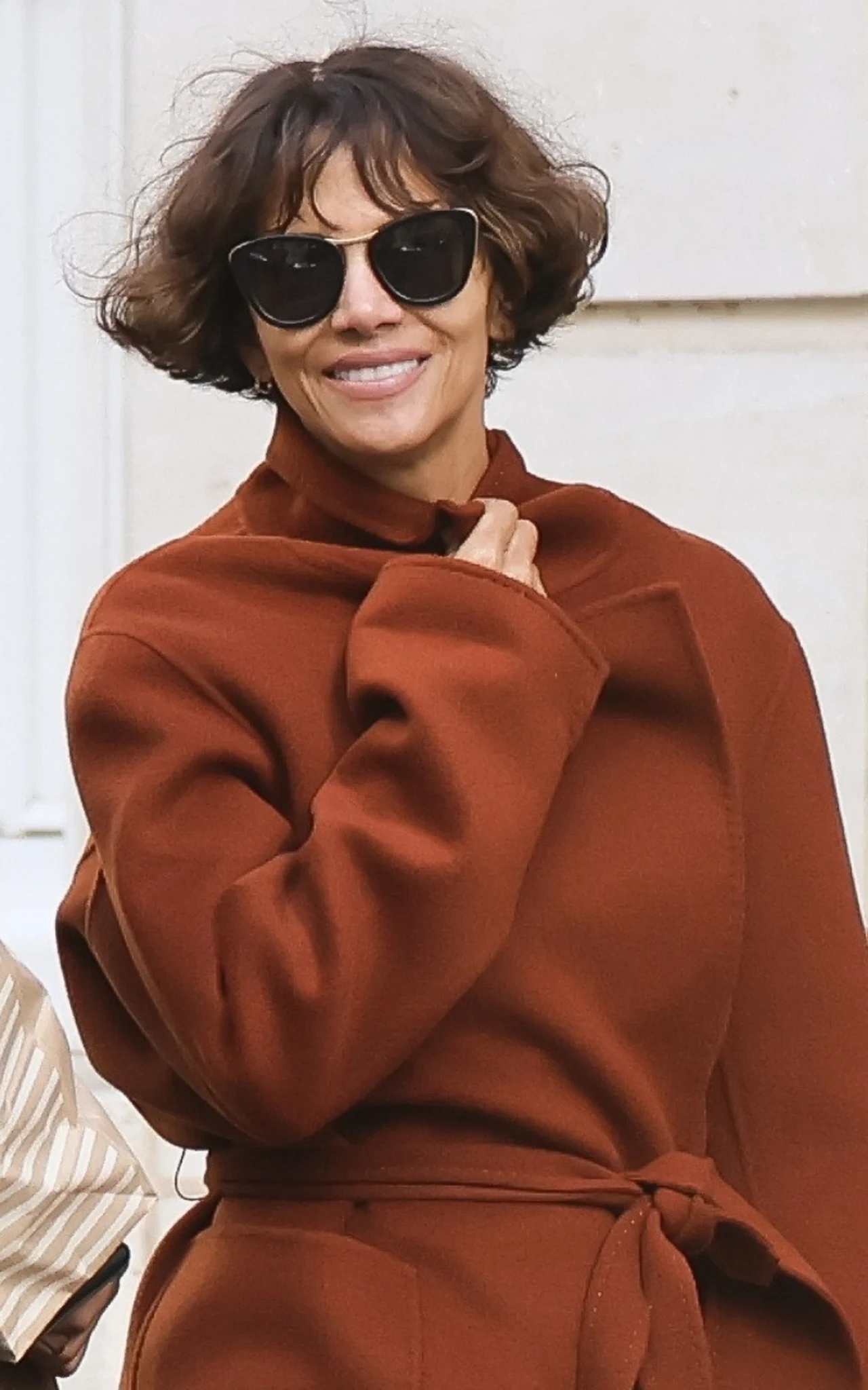 Halle Berry w nowej fryzurze zachwyca. Trudno uwierzyć, że ma 59 lat kobieta w krótkich, ciemnych włosach, ubrana w brązowy płaszcz przewiązany w talii, uśmiecha się i nosi duże, czarne okulary przeciwsłoneczne