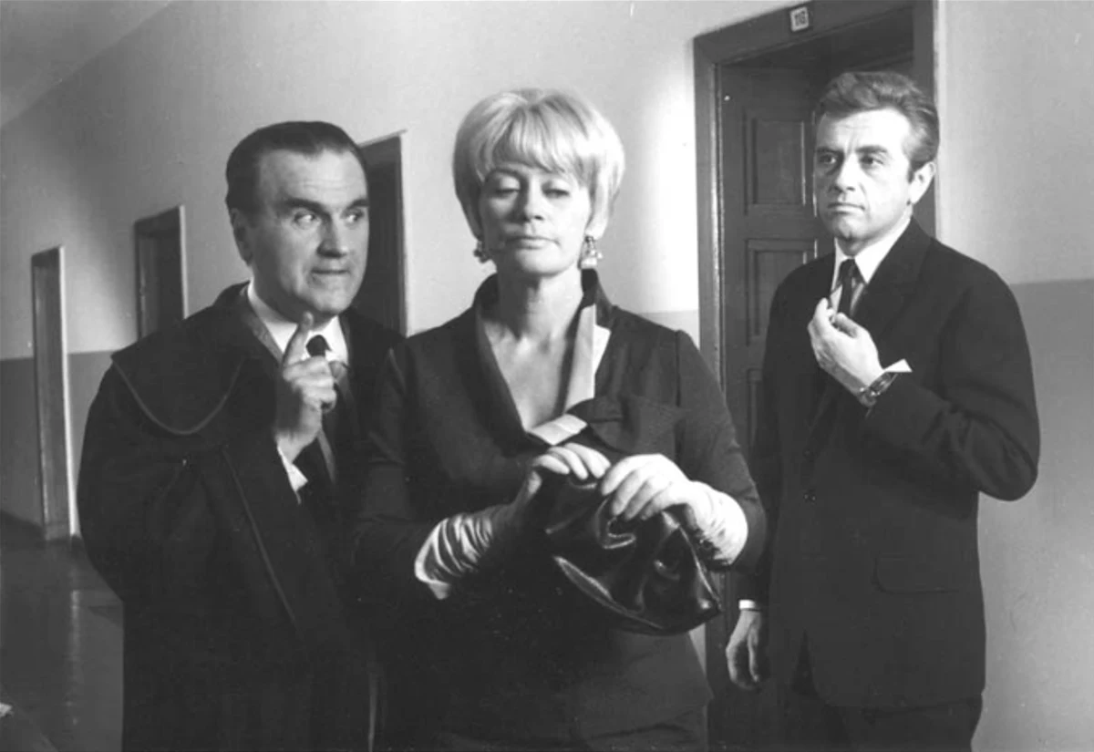 Stefan Witas, Alina Janowska i Andrzej Łapicki w filmie "Poradnik matrymonialny" (1967) Trójka dorosłych, elegancko ubranych osób stoi na korytarzu budynku, prezentując poważne miny i skupienie.