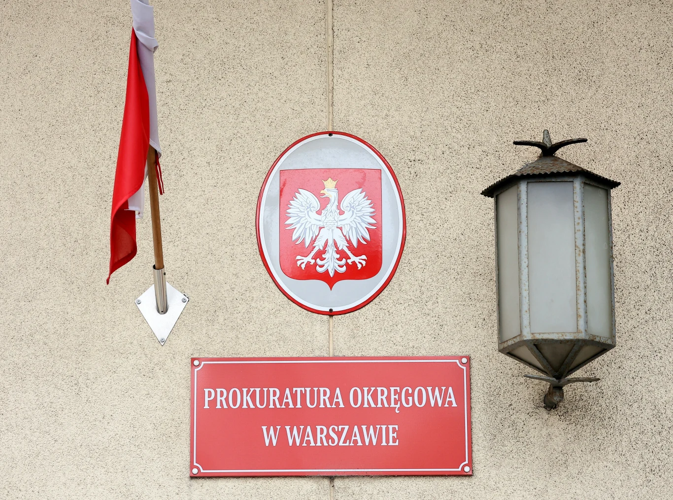 Marcin D. został zatrzymany Tablica "Prokuratura Okręgowa w Warszawie", godło Polski, flaga i lampa na jasnej elewacji budynku