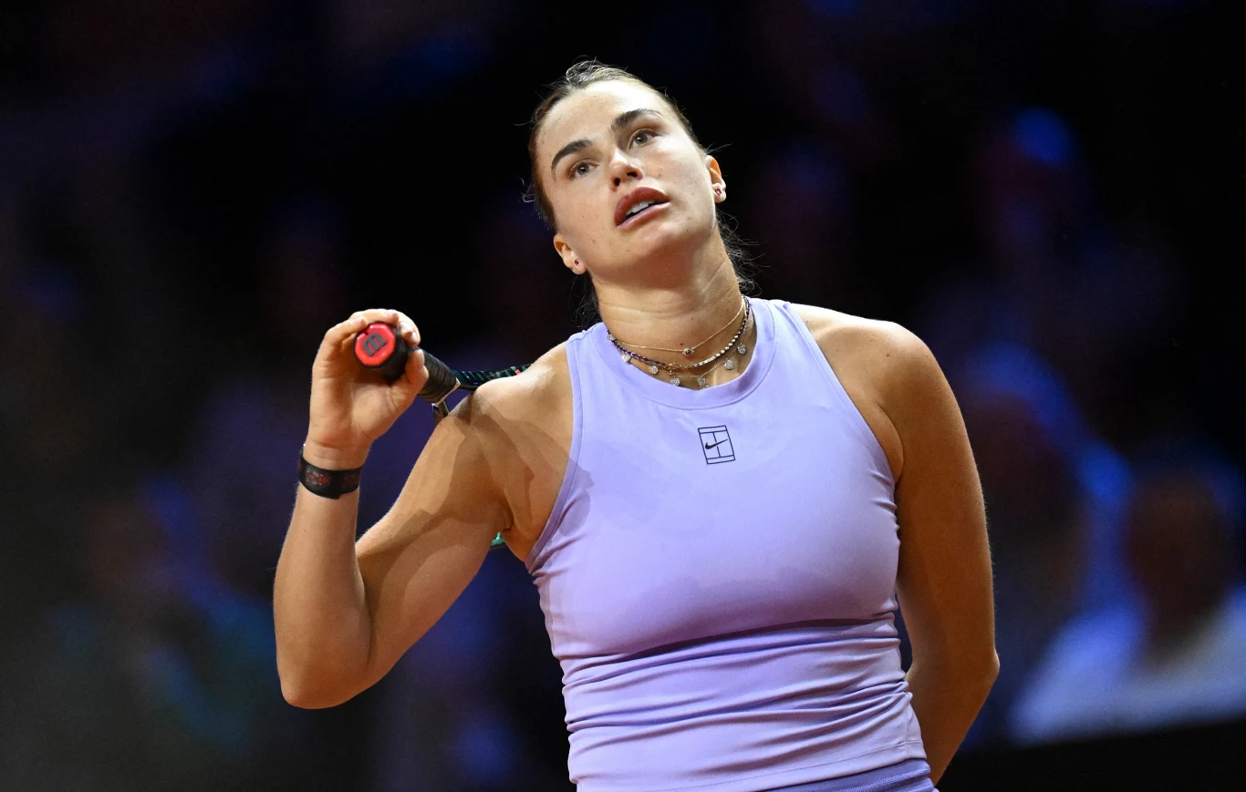 Aryna Sabalenka Aryna Sabalenka w liliowym stroju tenisowym z rakietą opartą o ramię na tle kortu.
