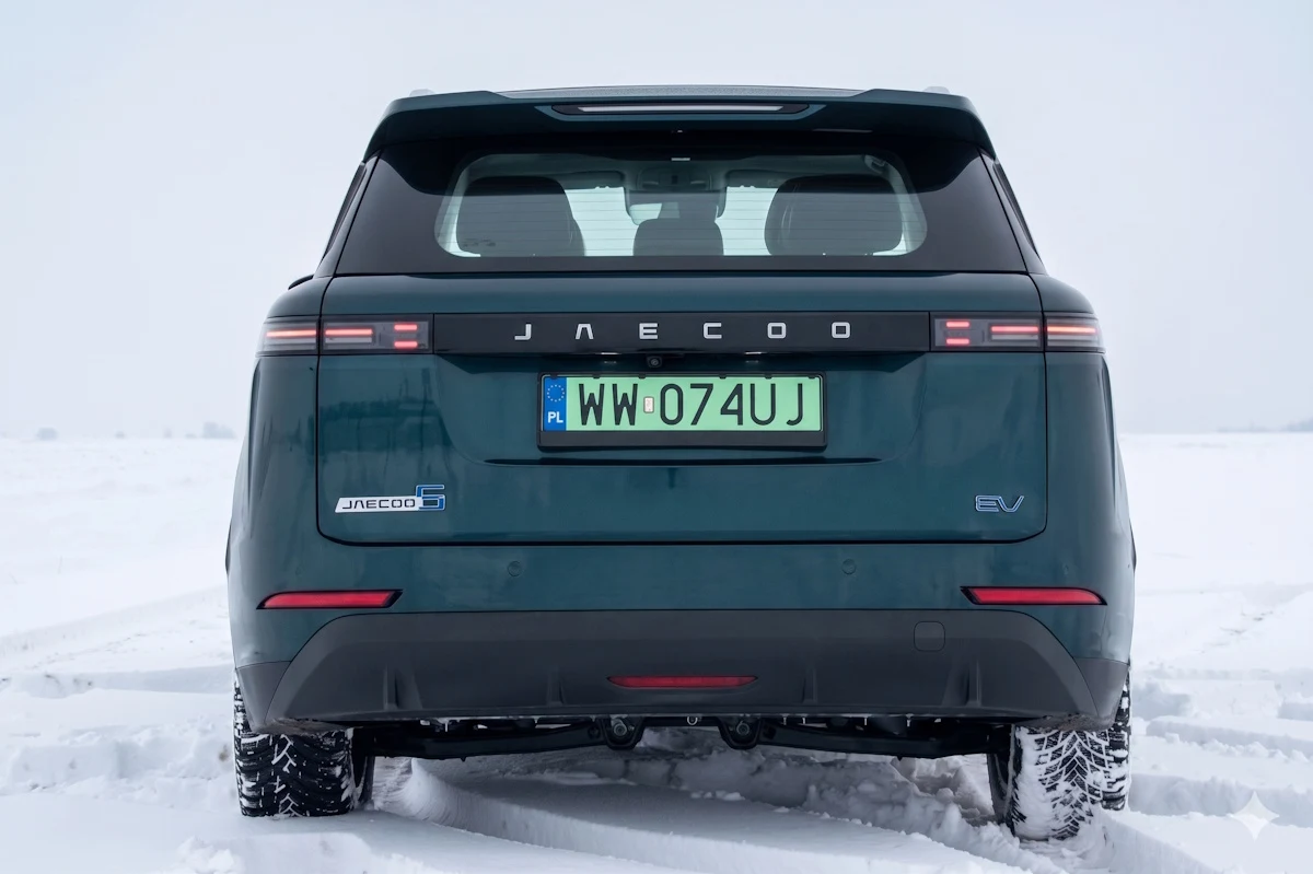 tył nowoczesnego elektrycznego SUV-a JAECOO z polskimi tablicami rejestracyjnymi, widoczne poziome światła LED i logo marki na śnieżnym podłożu