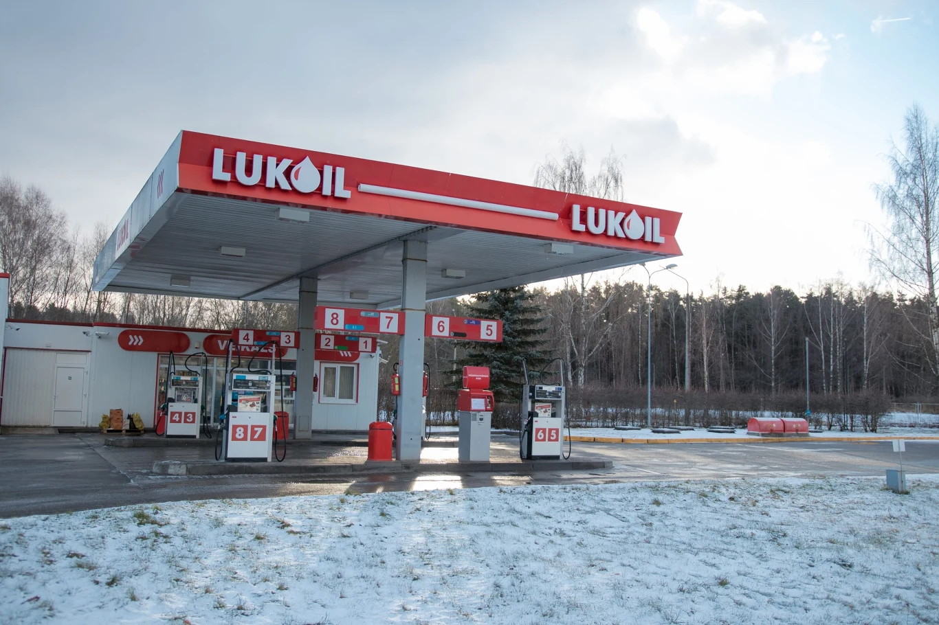 Do 29 października przedłużona została licencja zwalniająca stacje paliwowe Łukoilu poza Rosją z sankcji nałożonych na koncern Stacja benzynowa Lukoil z czerwonym zadaszeniem i logo, dystrybutory paliwa, śnieg i drzewa w tle