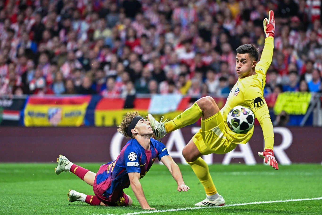 Fermin Lopez Bramkarz Atletico w żółtym stroju interweniuje nogą, powstrzymując Fermina Lopeza Barcelony na murawie.