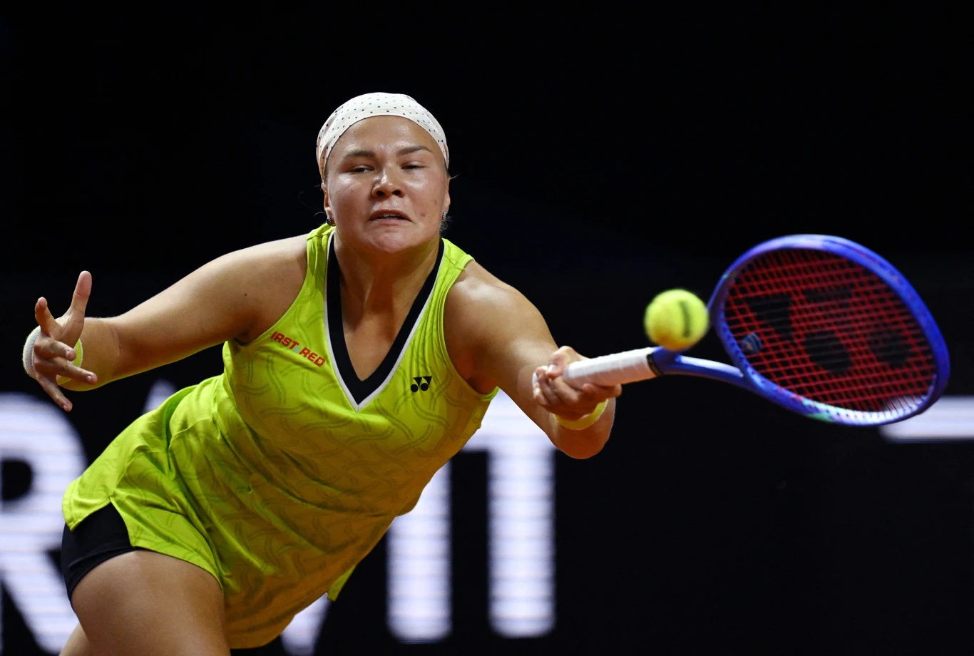 tenisistka w żółtym stroju uderza piłkę rakietą podczas intensywnej gry, skoncentrowana na ruchu i wysiłku