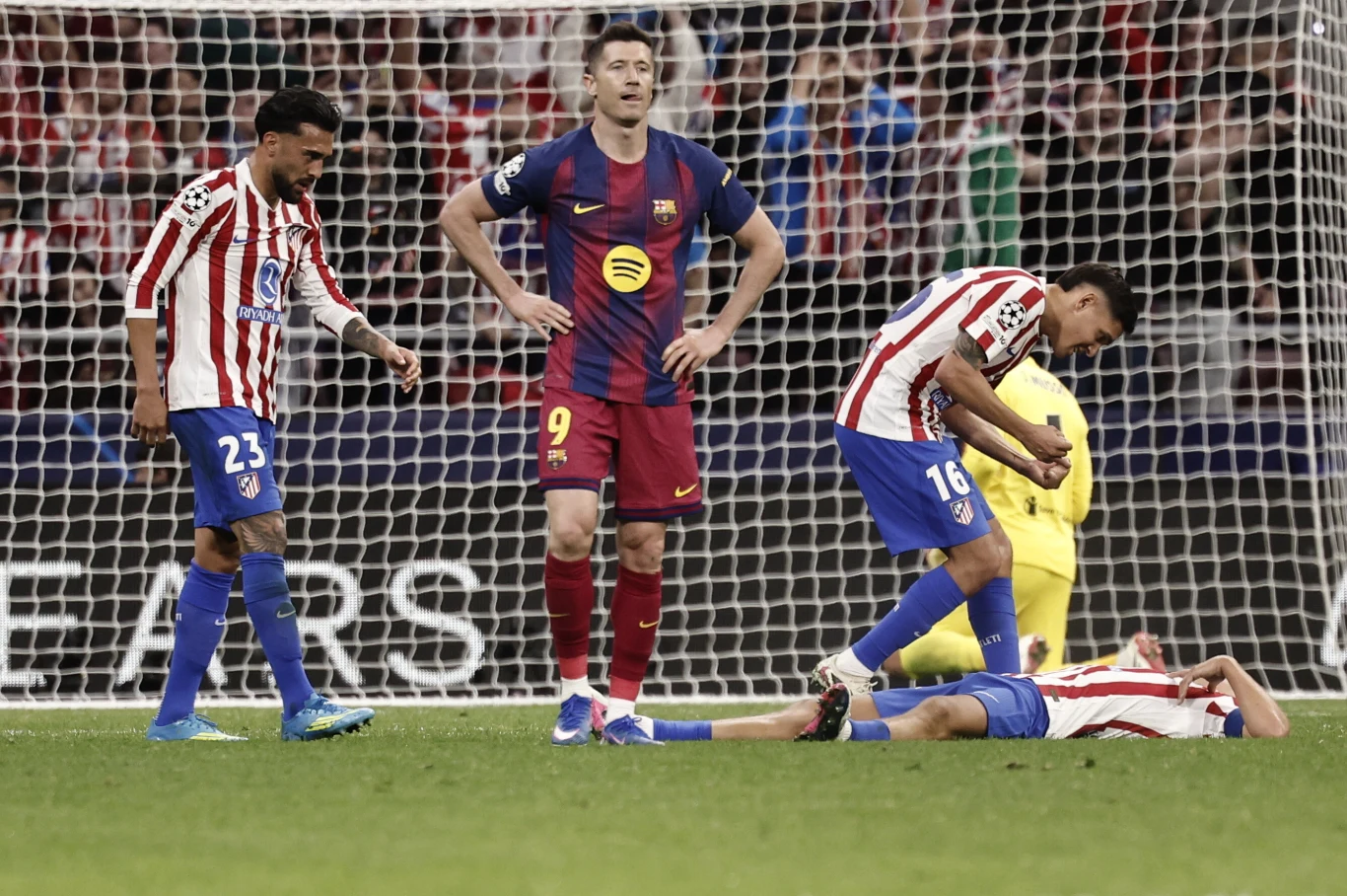 Robert Lewandowski w meczu z Atletico piłkarze Atlético Madryt i FC Barcelony znajdują się w polu karnym, jeden z zawodników leży na murawie trzymając się za nogę, a pozostali patrzą w jego stronę z wyraźnym zmartwieniem, w tle widoczne są siatka bramki i kibice