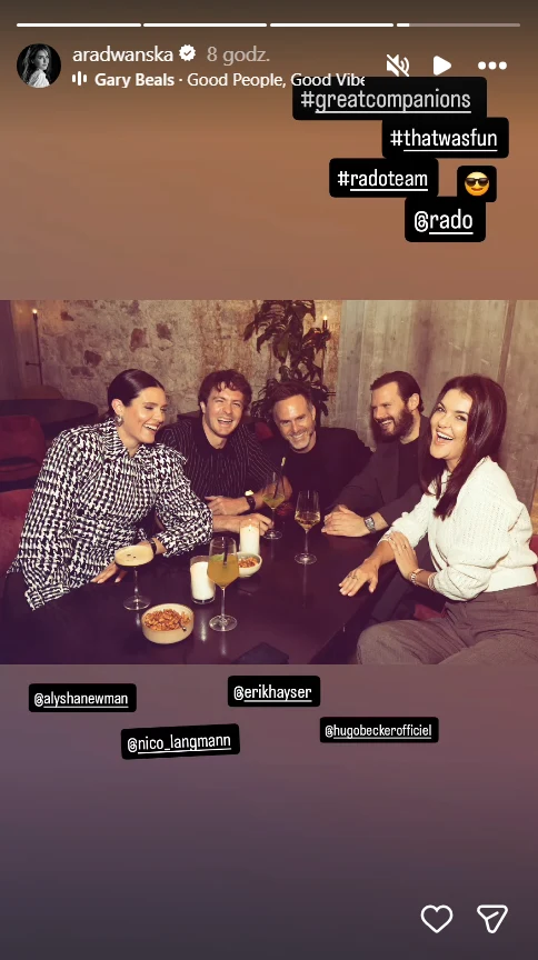 pięć osób siedzących przy stole w klimatycznie oświetlonej restauracji, wszystkie uśmiechnięte, przed nimi różne napoje oraz przekąski, atmosfera spotkania towarzyskiego