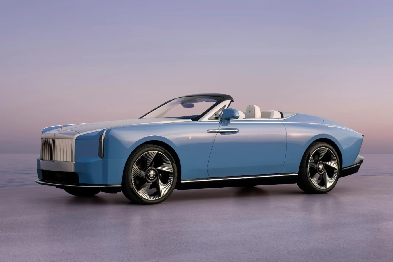 Powstanie zaledwie 100 egzemplarzy modelu Nightingale. Jasnoniebieski kabriolet Rolls-Royce Nightingale z białym wnętrzem, otwartym dachem i dużymi felgami na tle zachodu słońca