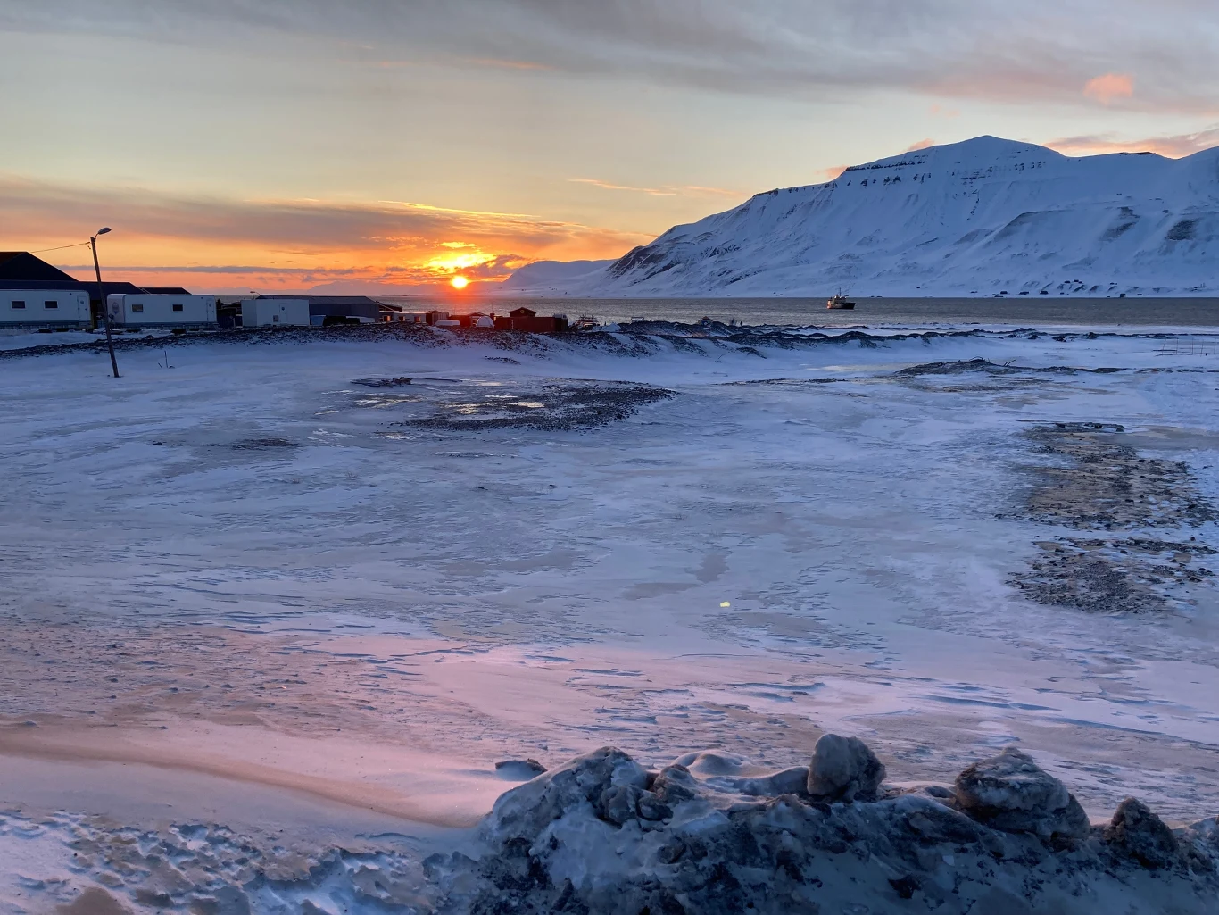 Dzień polarny na Svalbard; zdj. ilustracyjne Dzień polarny na Svalbard; ośnieżony krajobraz, niskie słońce, góry, zabudowania, zamrożone jezioro