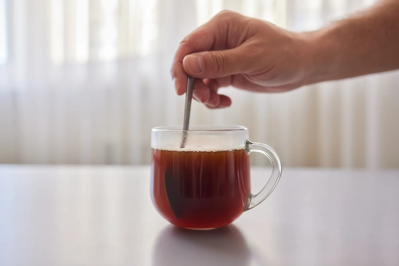 Dodaj do herbaty zamiast cukru. Serce ci podziękuje Szklanka herbaty mieszana łyżeczką, widoczna przezroczysta rączka, zamiast cukru polecana żurawina.