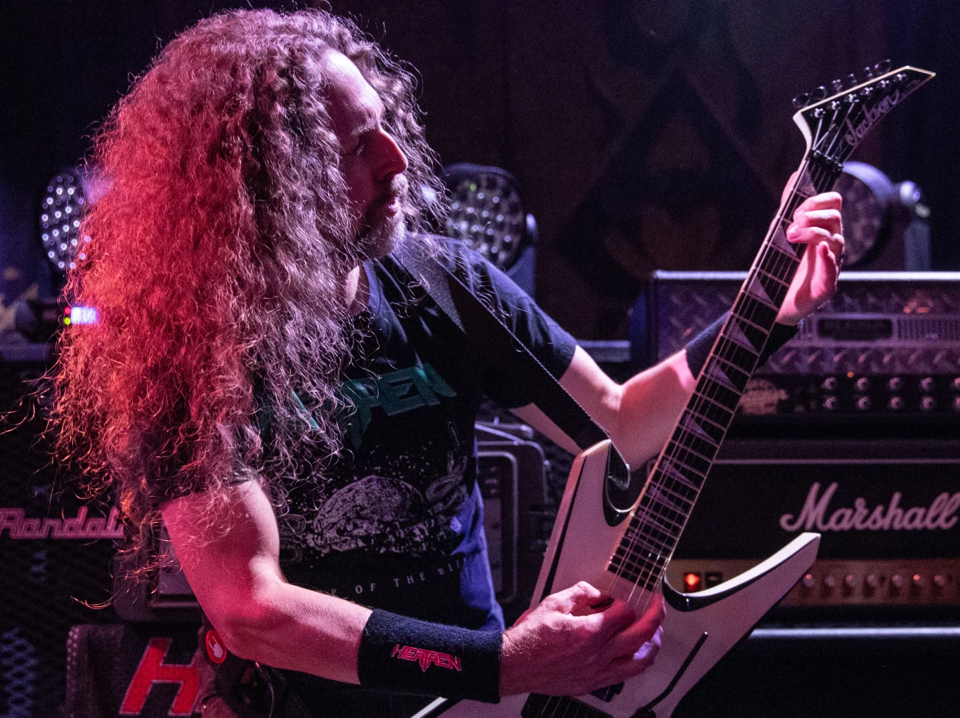 Kragen Lum (Heathen) w akcji Kragen Lum z Heathen gra na białej gitarze elektrycznej na tle wzmacniaczy Marshall i Randall podczas koncertu.
