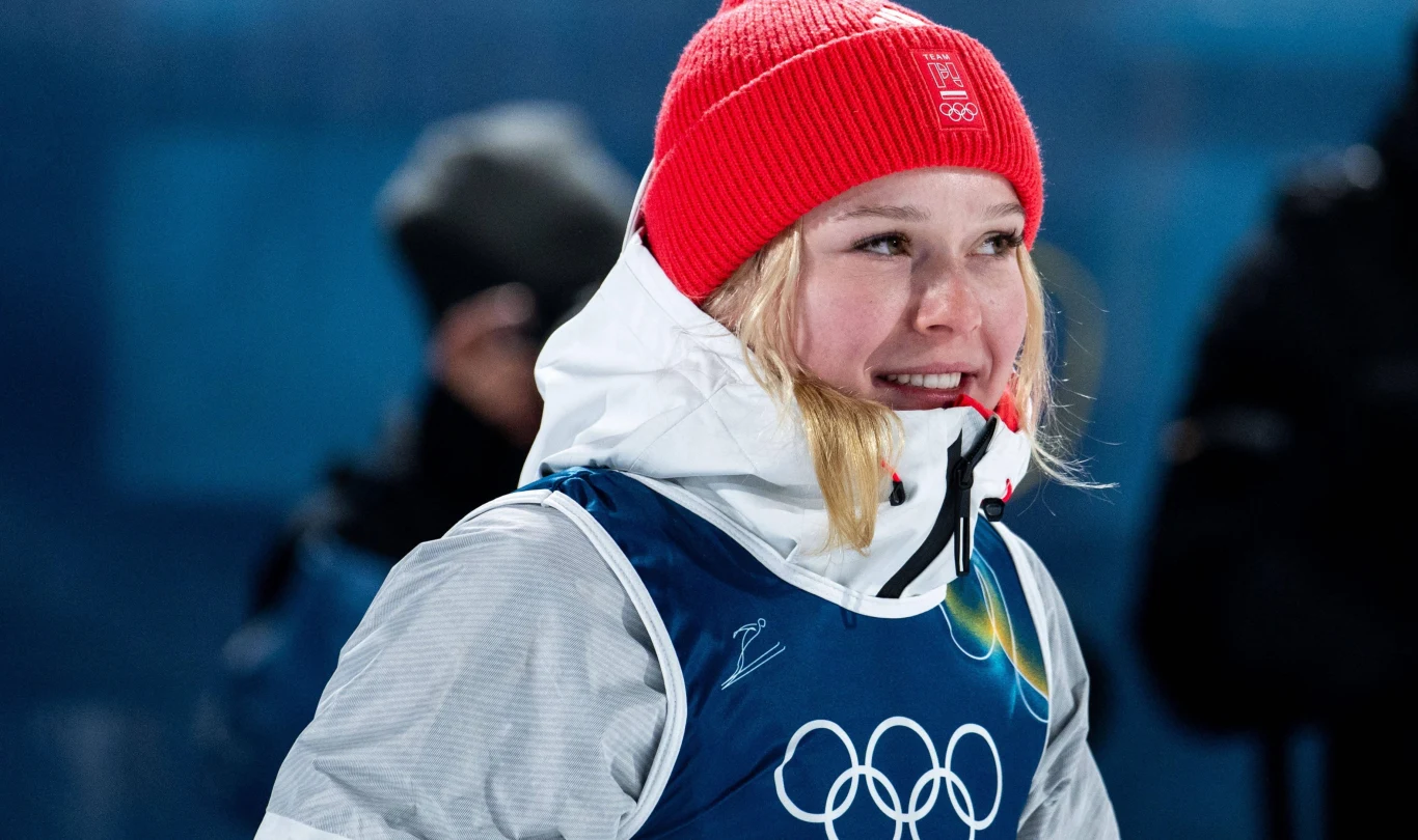 Pola Bełtowska Pola Bełtowska w czerwonej czapce, białej kurtce i niebieskiej kamizelce z symbolem olimpijskim na tle niebieskim