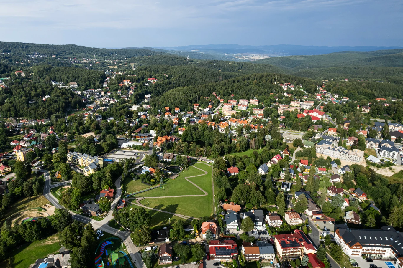 W Karkonoszach liczyli na turystów z Bliskiego Wschodu. Na zdjęciu Szklarska Poręba. Szklarska Poręba – panorama miasta otoczonego lasami i wzgórzami, widoczny park i gęsta zabudowa.