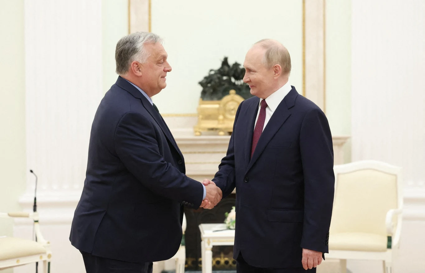 Premier Węgier Viktor Orban i prezydent Rosji Władimir Putin Dwóch mężczyzn w garniturach podaje sobie dłonie, stojąc naprzeciwko siebie w eleganckim, jasnym wnętrzu z ozdobnym kominkiem i jasnymi fotelami w tle.