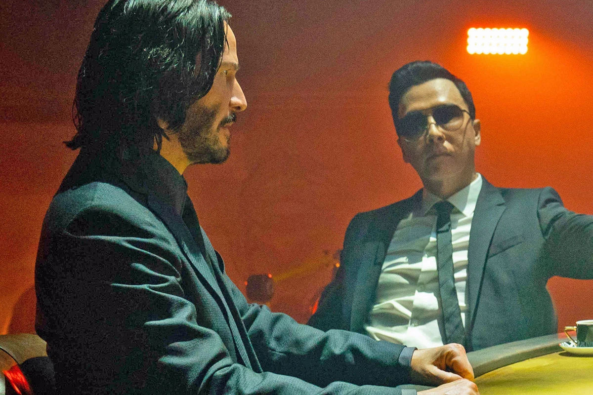 Keanu Reeves i Donnie Yen w scenie z filmu "John Wick 4" Keanu Reeves i Donnie Yen przy okrągłym stole w ciemnym wnętrzu na planie filmu "John Wick 4"