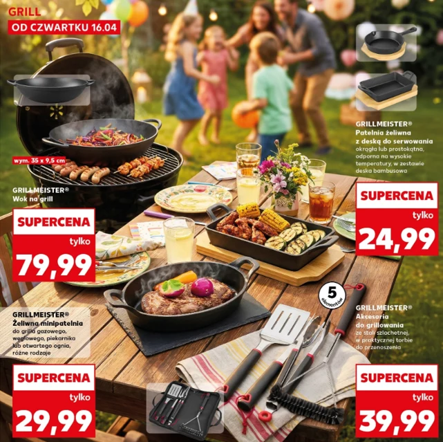 Duży grill ogrodowy z wokiem pełnym jedzenia, kilka żeliwnych patelni z grillowanymi warzywami i mięsem oraz zestaw narzędzi do grillowania na drewnianym stole, wokół którego stoi grupa ludzi w letnich ubraniach, rozmawiających i trzymających napoje, w...
