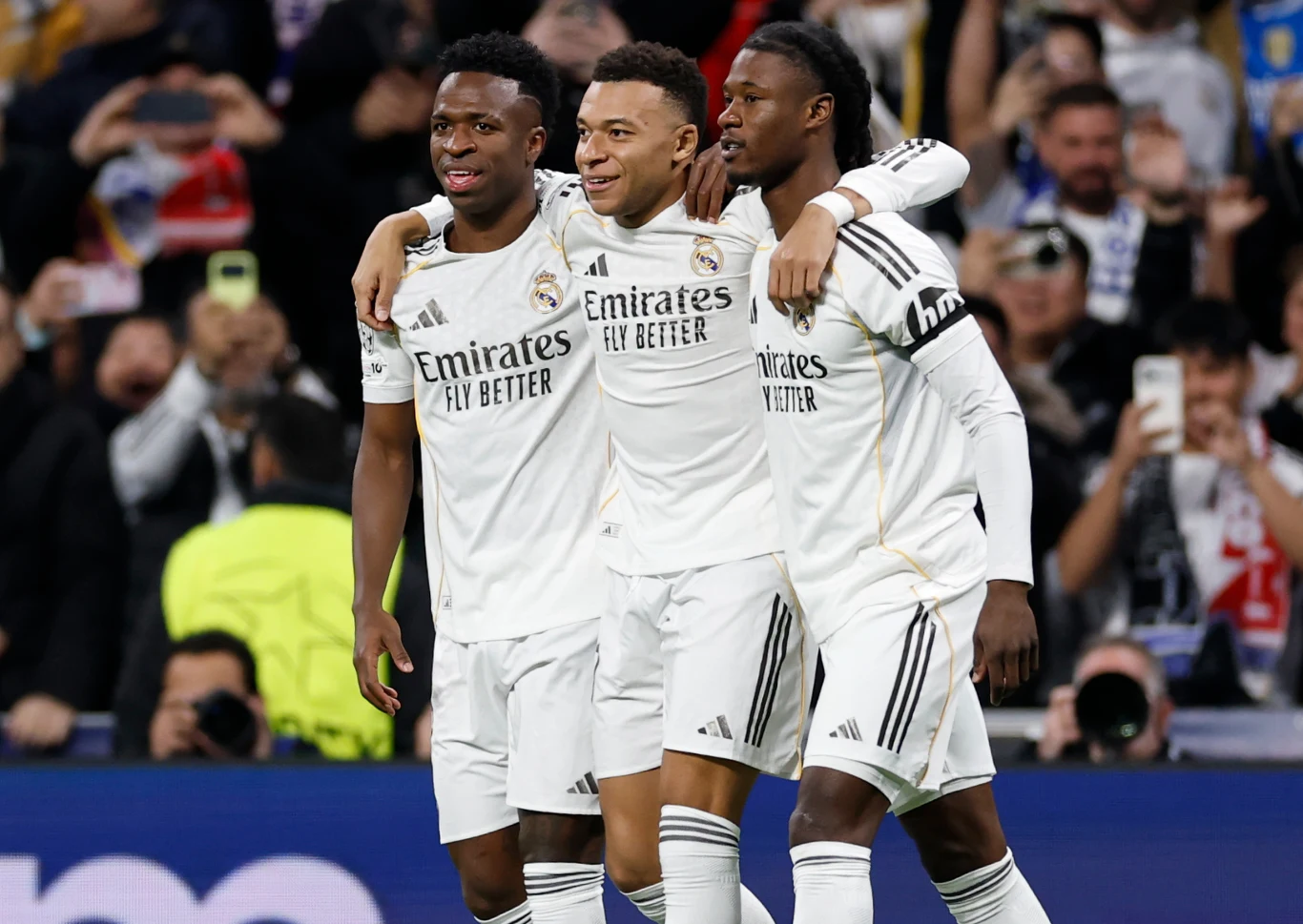 Vinicius Junior, Kylian Mbappe oraz Eduardo Camavinga Vinicius Junior, Kylian Mbappe i Eduardo Camavinga w białych strojach Realu Madryt świętują na boisku.