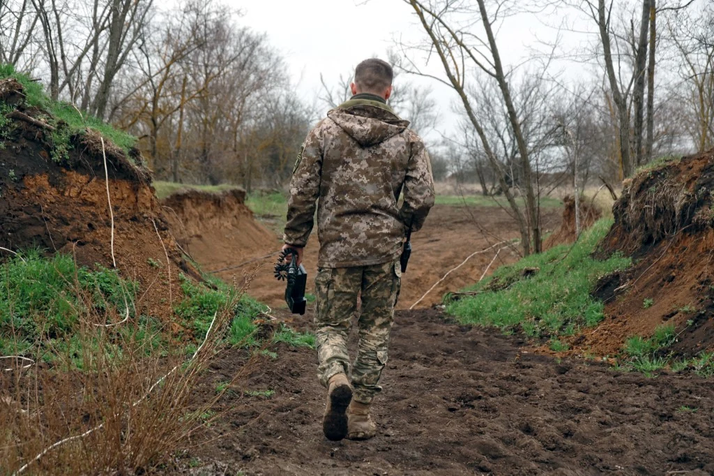 Polak został skazany przez Sąd Najwyższy Ługańskiej Republiki Ludowej za walkę po stornie Ukrainy (zdj. ilustracyjne) Żołnierz w mundurze maskującym z dronem idzie przez błotnisty teren wśród drzew, zdjęcie ilustracyjne.