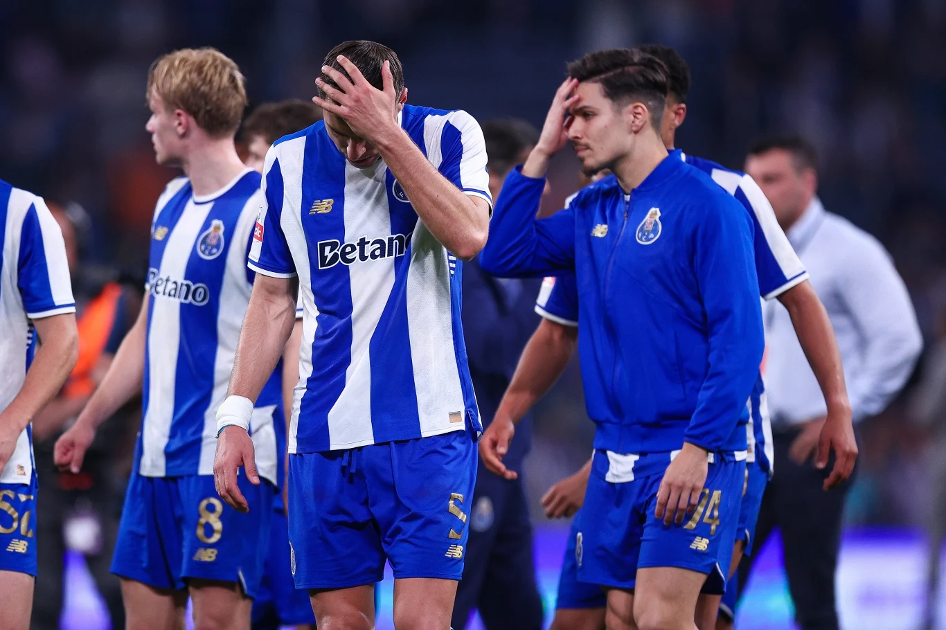 Jan Bednarek z innymi piłkarzami FC Porto piłkarze drużyny FC Porto w niebiesko-białych strojach opuszczają boisko ze smutnymi wyrazami twarzy, kilku z nich zakrywa dłonią twarz w geście rozczarowania, tło rozmazane, co podkreśla emocje sportowców