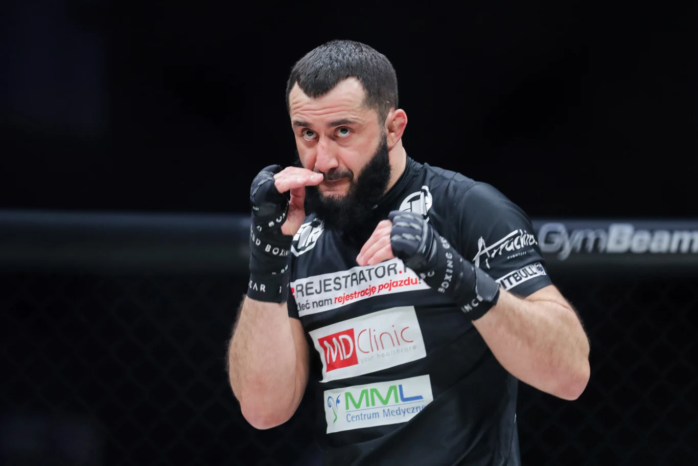 Mamed Chalidow Mamed Chalidow, zawodnik MMA w czarnej koszulce i rękawicach, przygotowuje się do walki na arenie