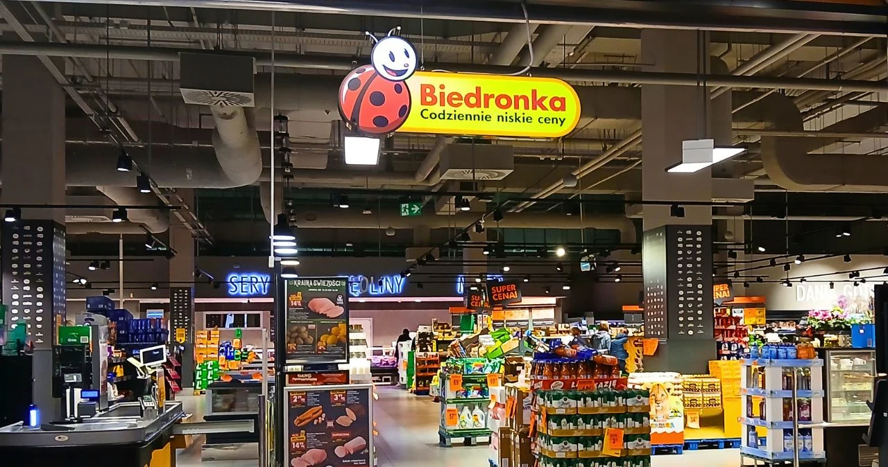 Kubota wraca do Biedronki i znowu wywoła zamieszanie. Te rzeczy rozejdą się błyskawicznie Wnętrze supermarketu Biedronka z logo, szerokimi alejkami i regałami z produktami spożywczymi.
