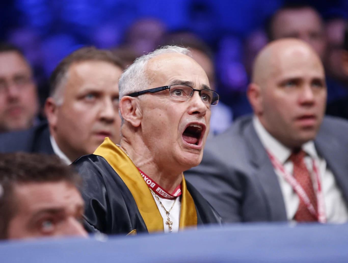 Roger Bloodworth starszy mężczyzna w okularach i czarno-żółtym stroju, z otwartymi ustami w wyrazie silnych emocji, siedzi wśród innych mężczyzn podczas wydarzenia sportowego