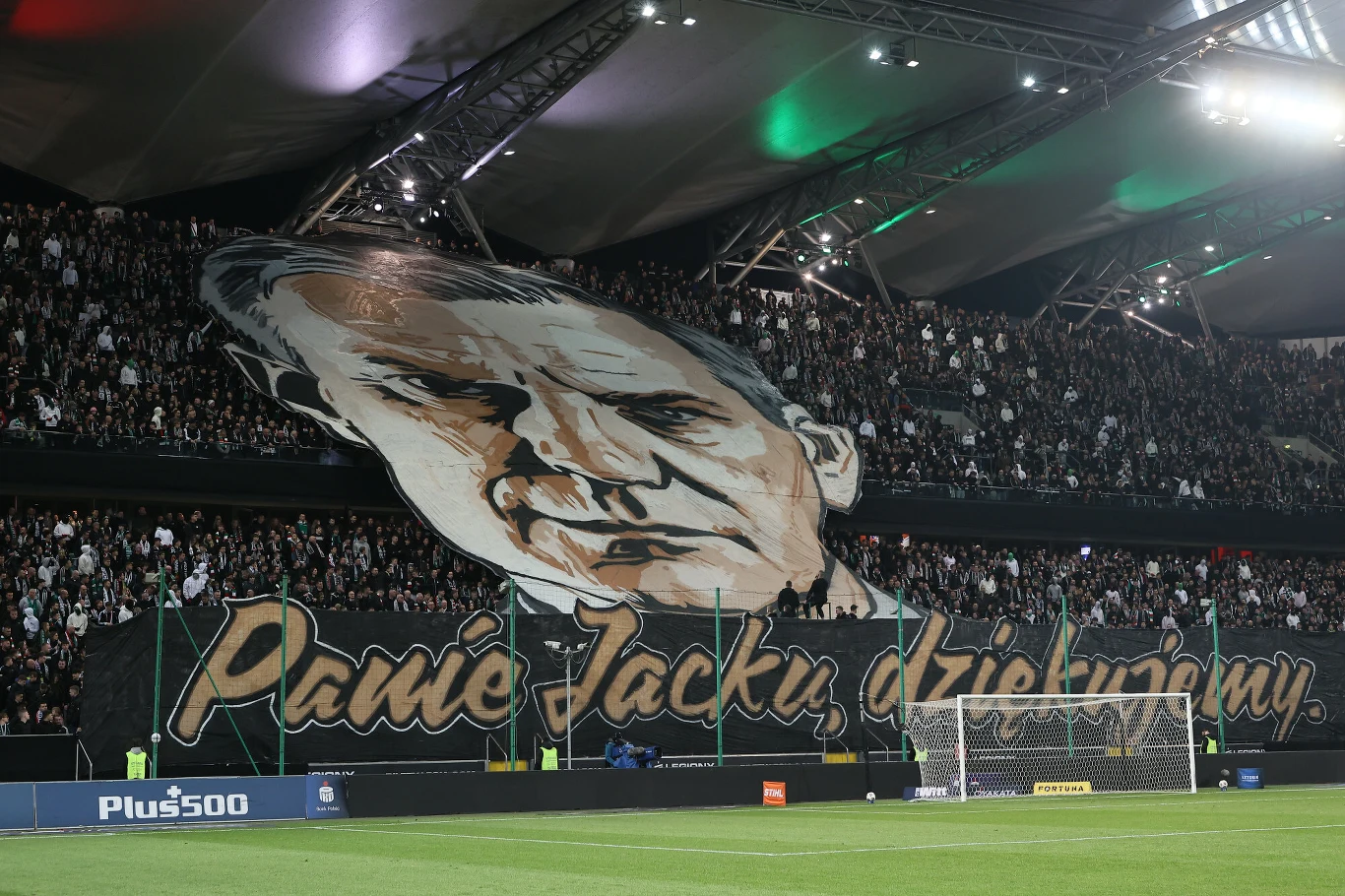 ogromna choreografia kibiców na trybunach stadionu piłkarskiego, przedstawiająca wielki portret mężczyzny oraz napis „Panie Jacku, dziękujemy”