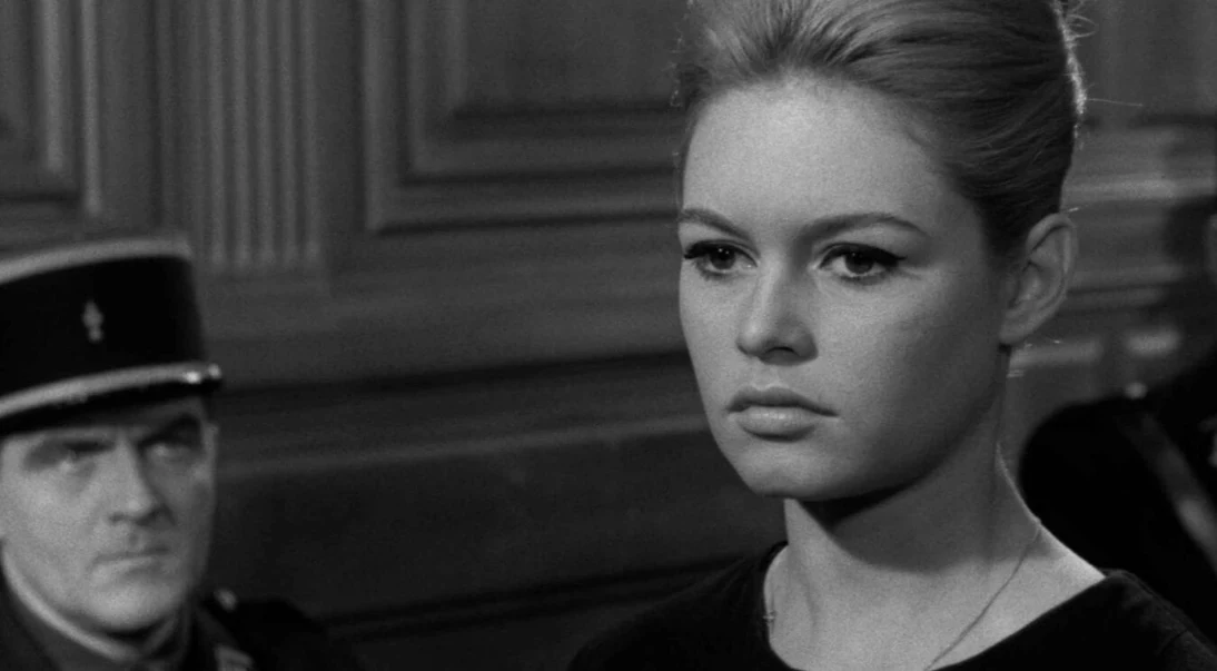 Kadr z filmu "Prawda", fot. Timeless Film Festival Warsaw młoda kobieta o poważnym wyrazie twarzy stoi na pierwszym planie w eleganckim wnętrzu, za nią widoczny jest mężczyzna w mundurze policyjnym