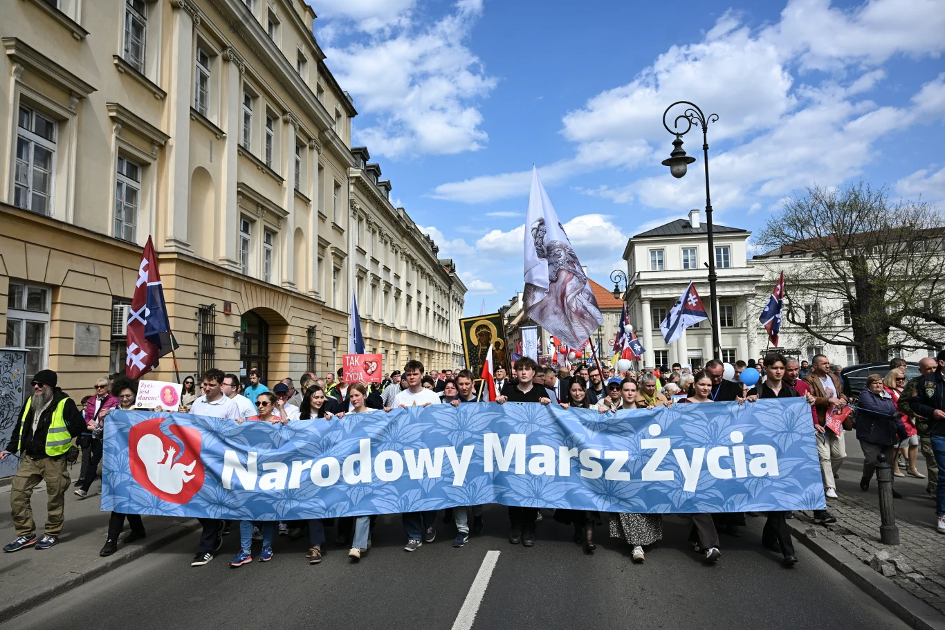 Ulicami Warszawy przeszedł Narodowy Marsz Życia Maszerujący trzymają baner z hasłem "Narodowy Marsz Życia", w tle ikona Matki Boskiej i transparenty z hasłami pro-life.
