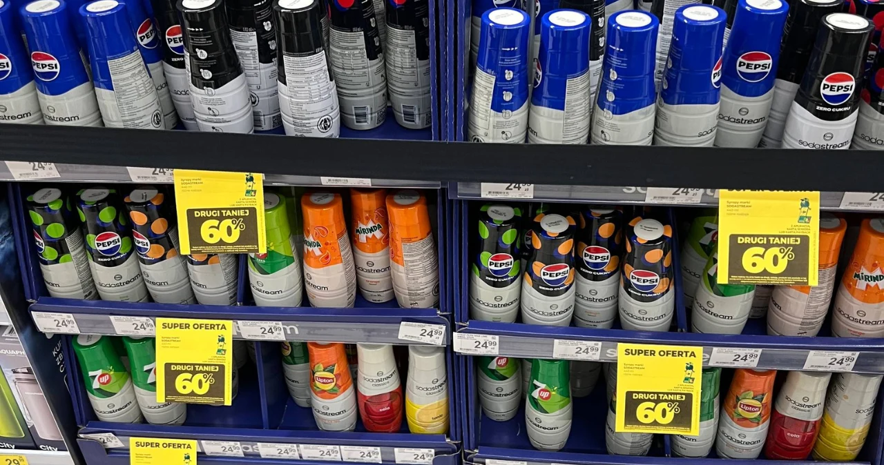 Carrefour robi wielką wyprzedaż SodaStream – rabaty sięgają 60% Półki sklepowe Carrefour z napojami SodaStream i żółtymi etykietami informującymi o promocji -60% na drugi produkt.