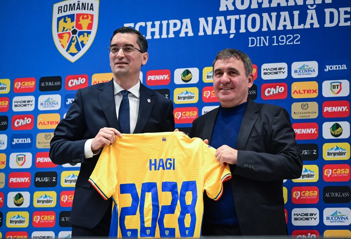 Gheorghe Hagi nowym selekcjonerem reprezentacji Rumunii Dwaj mężczyźni w eleganckich ubraniach stoją przed niebieskim tłem z logo rumuńskiej federacji piłkarskiej, trzymając żółtą koszulkę z nazwiskiem Hagi i numerem 2028.