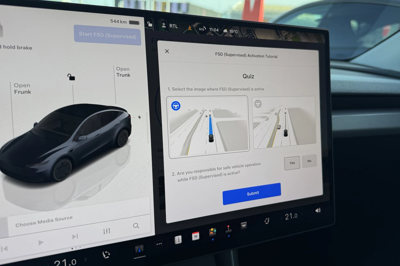 Ekran dotykowy w samochodzie Tesla prezentujący panel sterowania pojazdu po lewej stronie oraz quiz dotyczący funkcji FSD Supervised z wizualizacjami jazdy autonomicznej po prawej stronie; czytelny interfejs z widocznymi ikonami, przyciskami i informac...