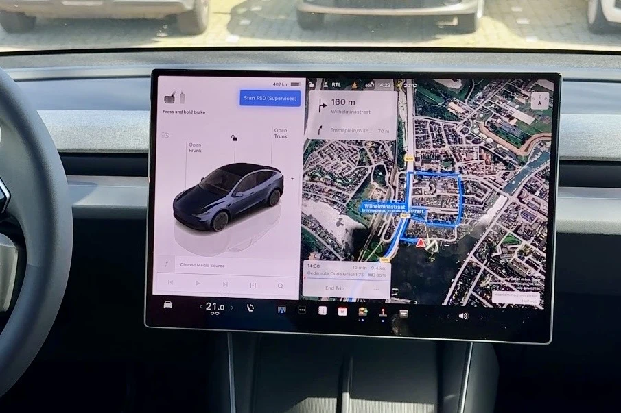 centralny ekran dotykowy samochodu Tesla z wyświetlonymi informacjami o pojeździe po lewej stronie oraz nawigacją GPS z widokiem mapy po prawej stronie